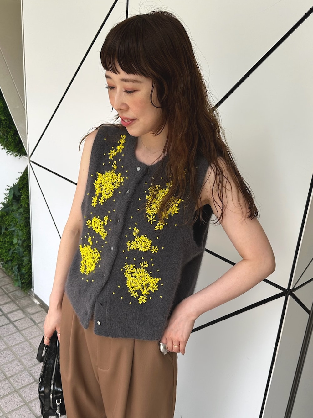 グレー系のベスト、ブラック系のハンドバッグ、ブラック系のブーツを着用したレディースの夏コーディネートの5枚目の写真