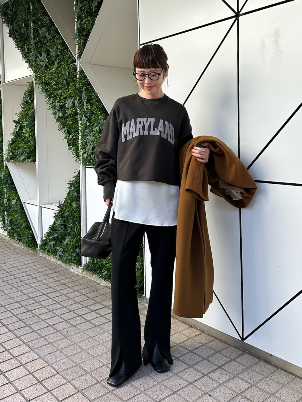 イエロー系のチェスターコート、ブラック系のスラックス、ブラック系のブーツを着用したレディースの秋コーディネートの5枚目の写真