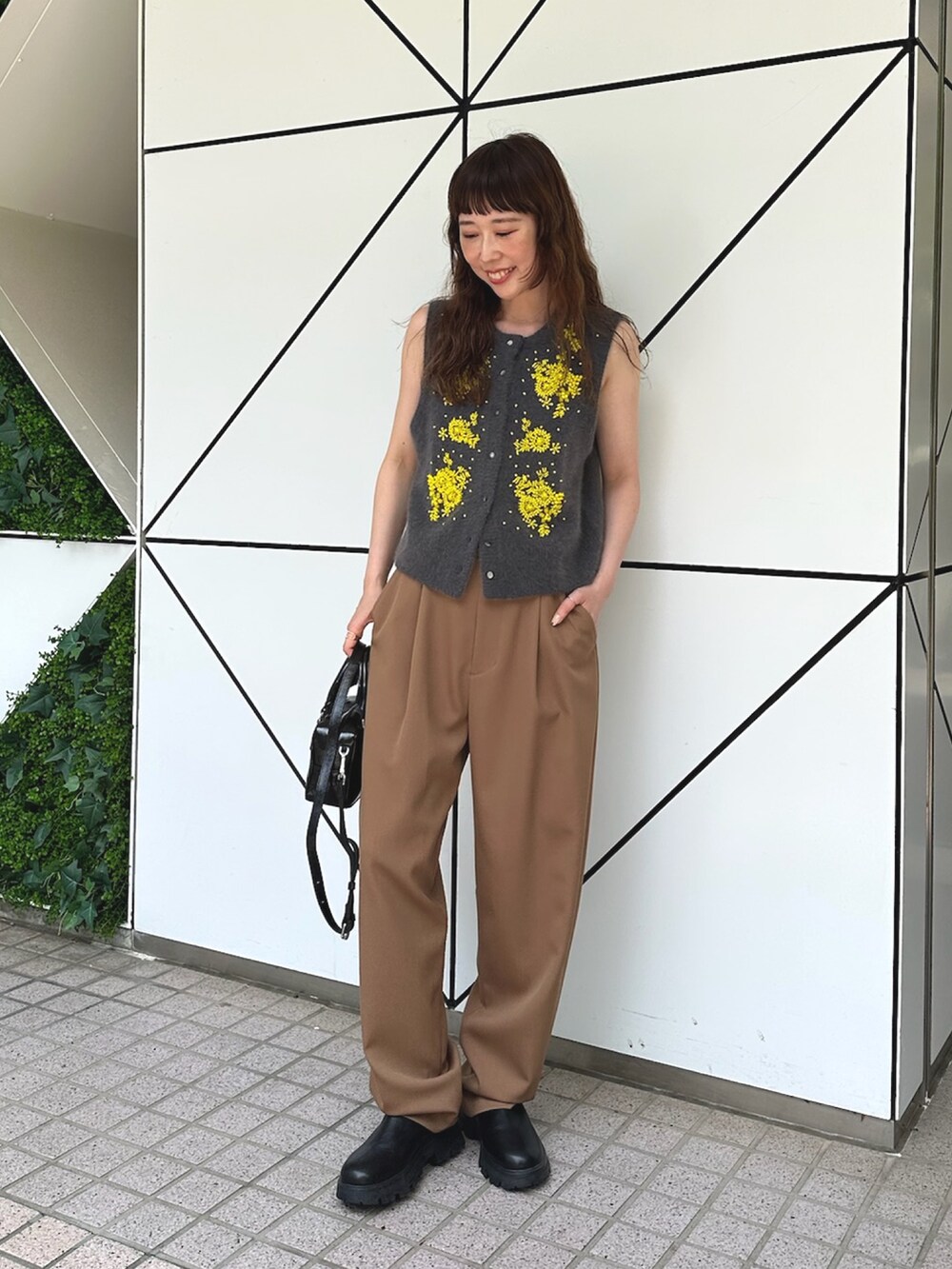 グレー系のベスト、ブラック系のハンドバッグ、ブラック系のブーツを着用したレディースの夏コーディネートの4枚目の写真