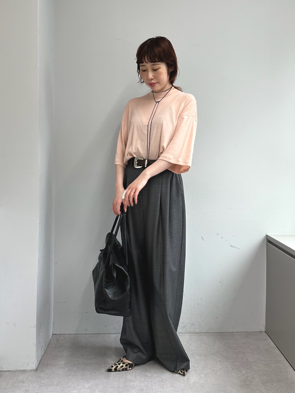 グレー系のスラックス、ブラック系のボストンバッグ、イエロー系のパンプスを着用したレディースの夏コーディネートの3枚目の写真