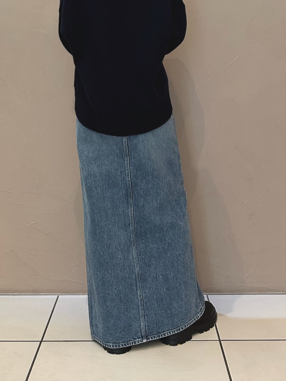 ブルー系のデニムスカート、ブラック系のブーツ、ブラウン系のハンドバッグを着用したレディースの夏コーディネートの3枚目の写真