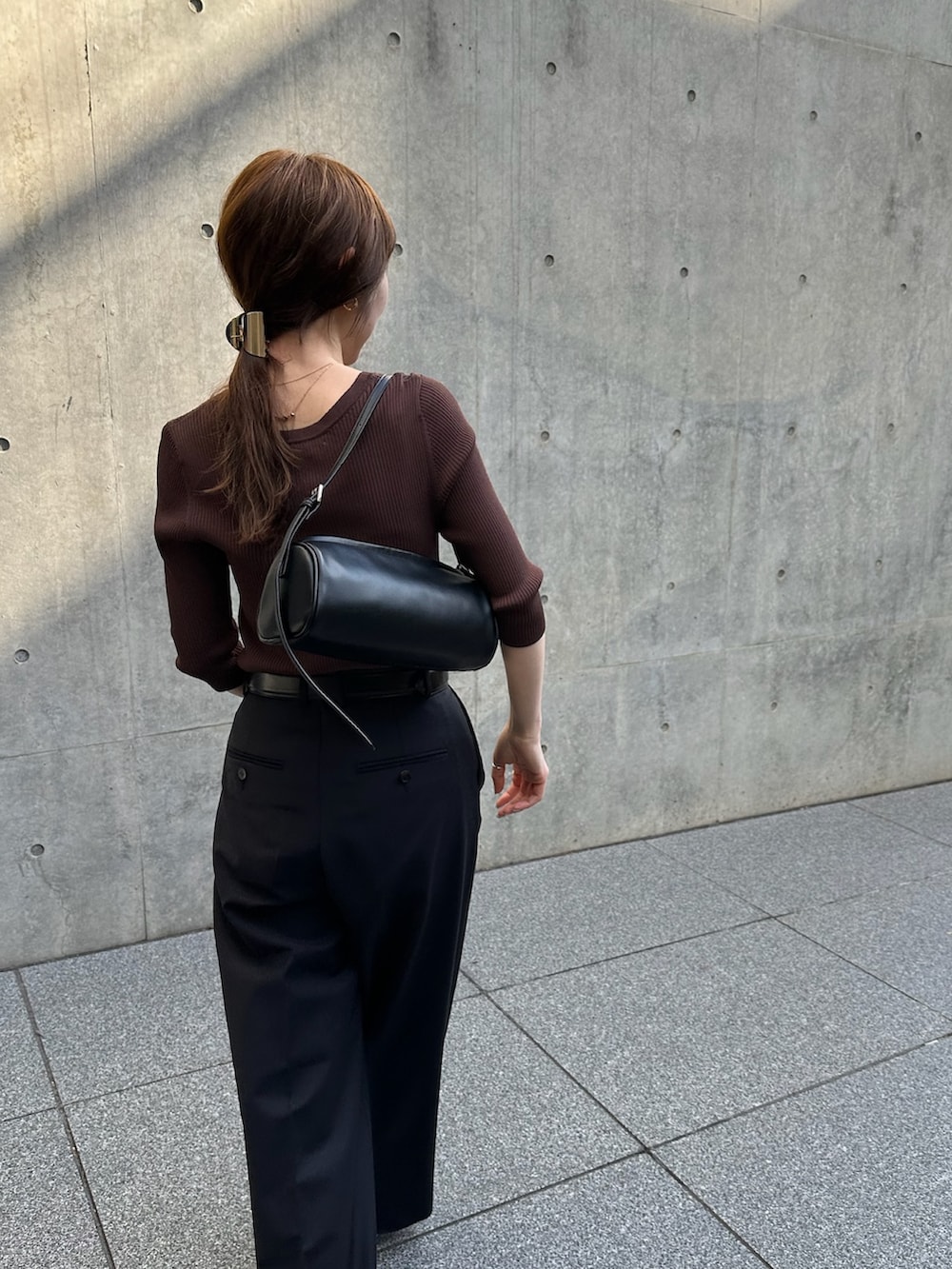 ブラウン系のニット/セーター、グレー系のスラックスを着用したレディースの春コーディネートの3枚目の写真