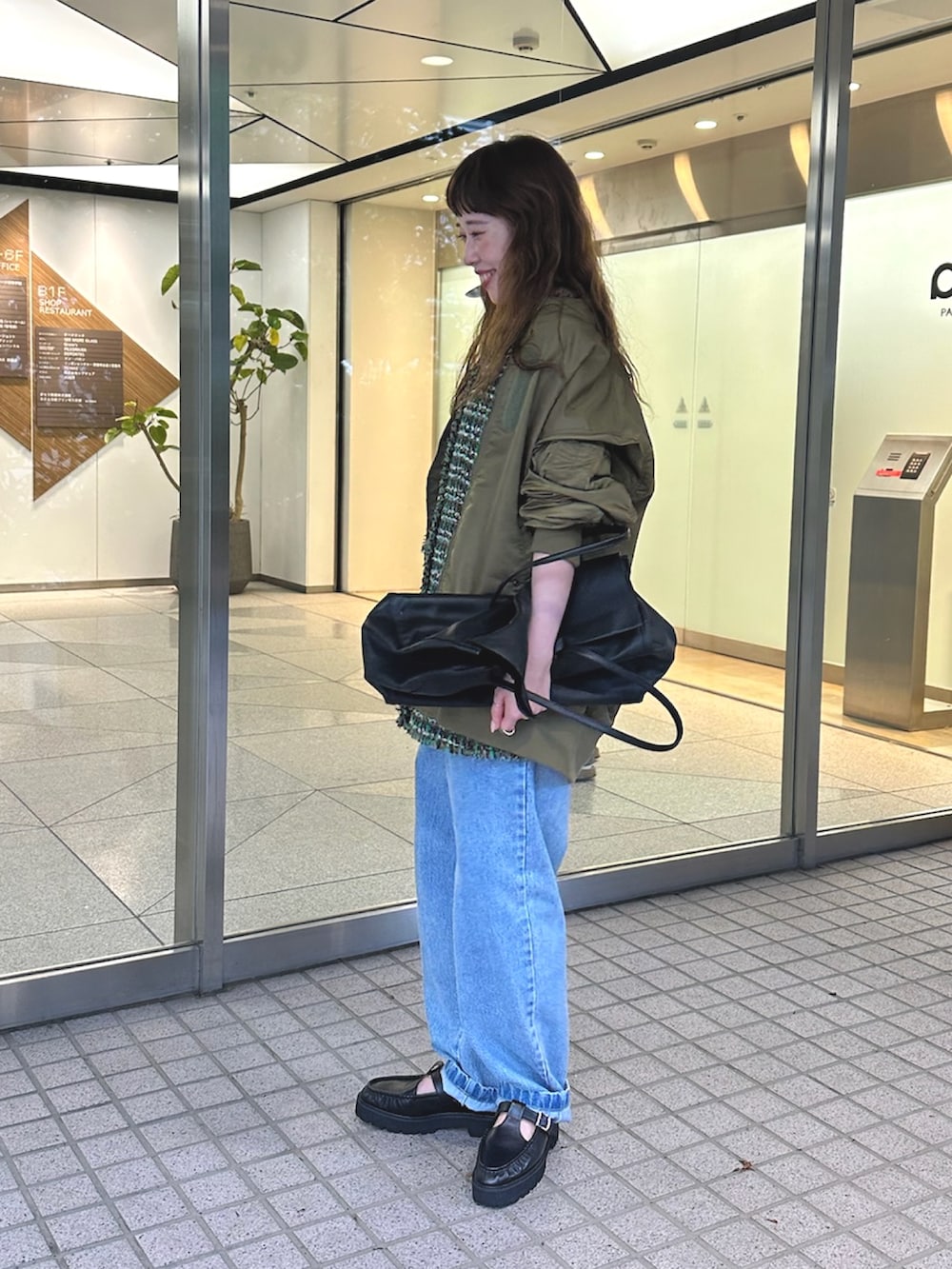 グリーン系のMA-1、ブルー系のデニムパンツ、ブラック系のボストンバッグを着用したレディースの夏コーディネートの3枚目の写真