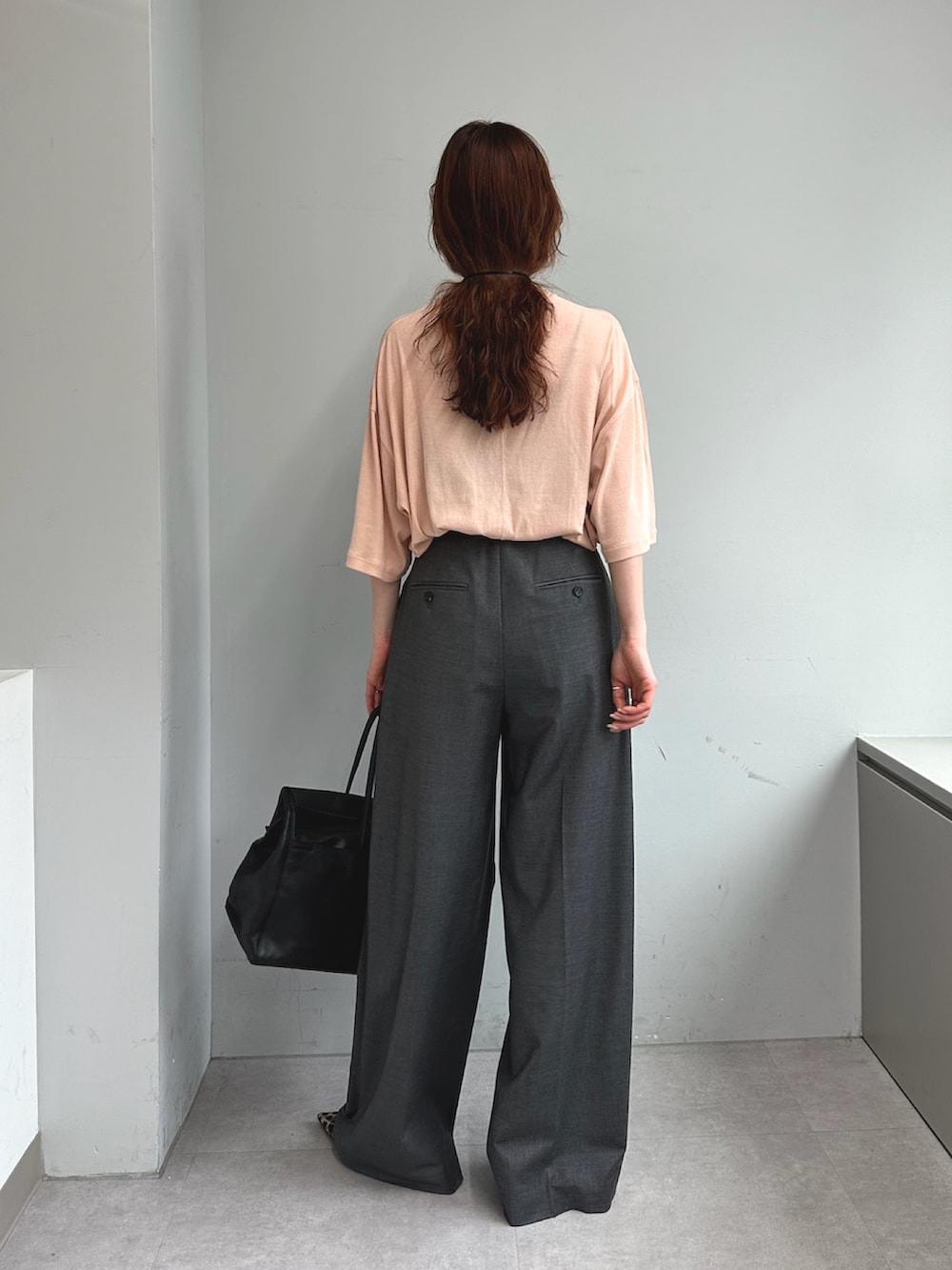 グレー系のスラックス、ブラック系のボストンバッグ、イエロー系のパンプスを着用したレディースの夏コーディネートの4枚目の写真