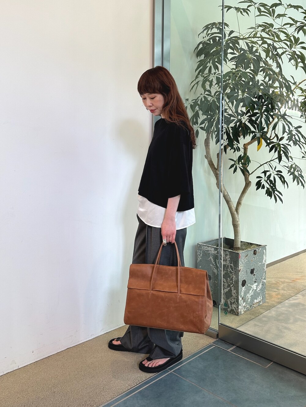 グレー系のスラックス、イエロー系のボストンバッグ、ホワイト系のシャツ/ブラウスを着用したレディースの夏コーディネートの5枚目の写真