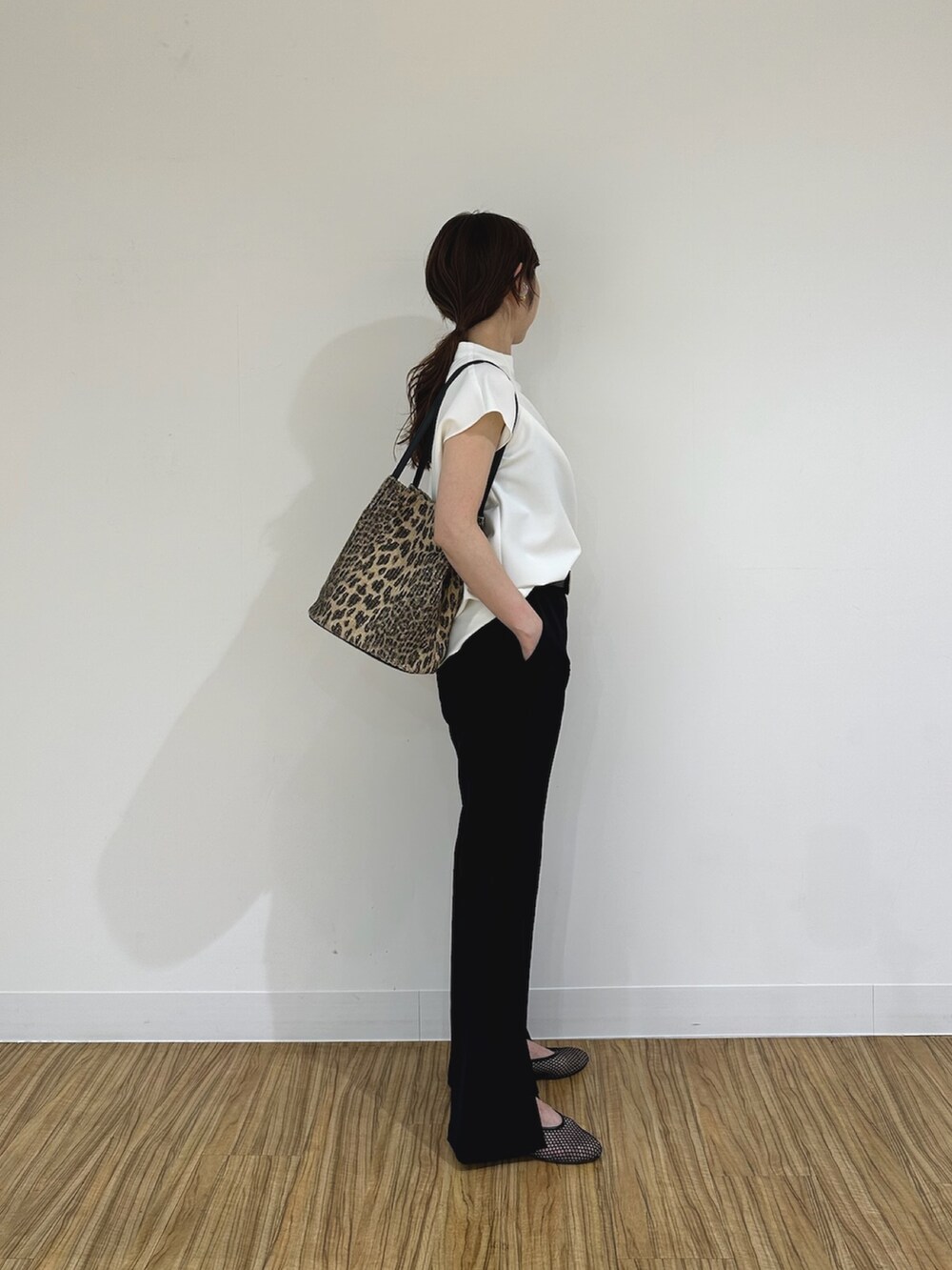 ブラック系のスラックス、ブラック系のパンプス、ホワイト系のシャツ/ブラウスを着用したレディースの夏コーディネートの4枚目の写真