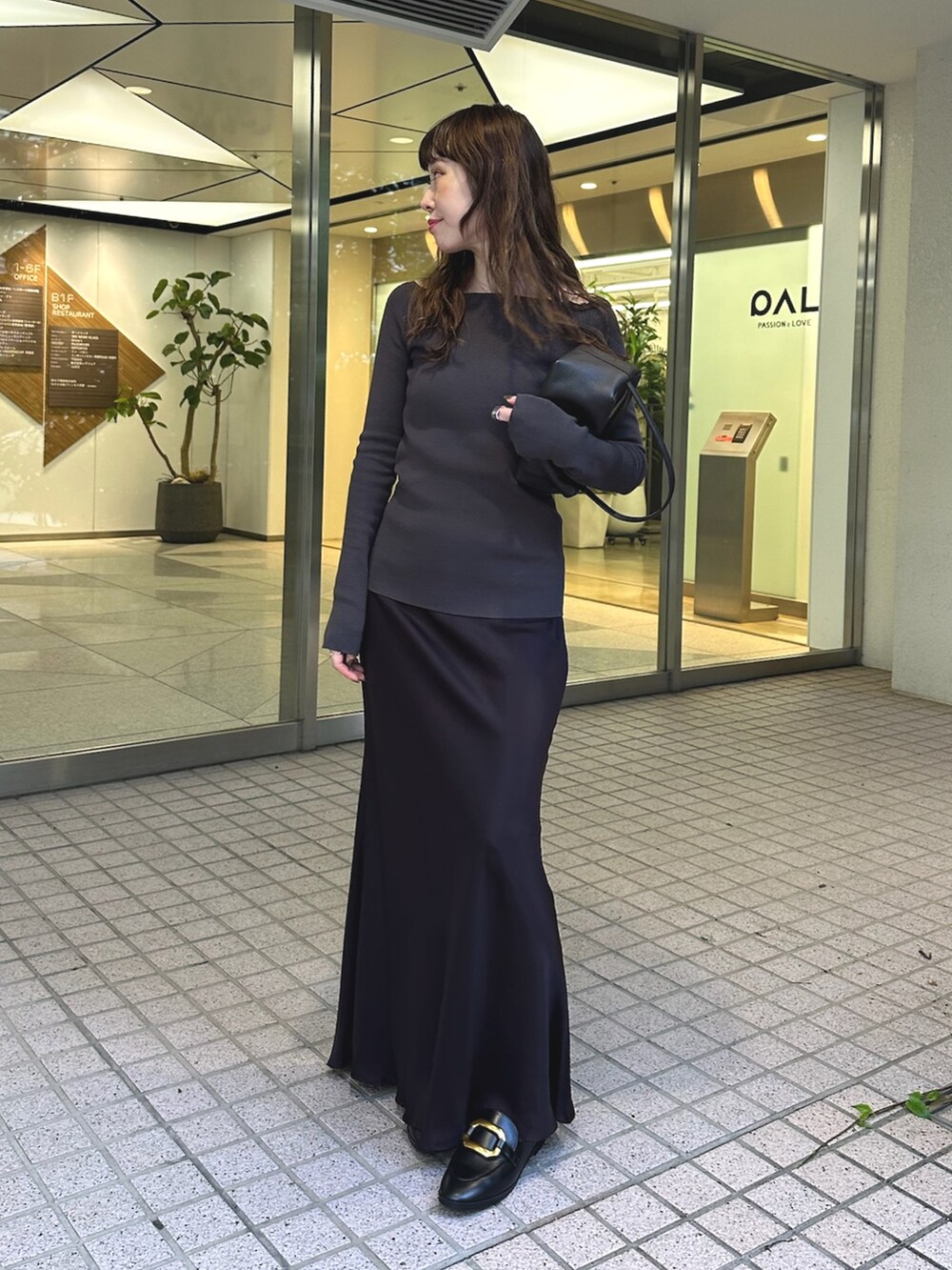 ブラック系のスカート、ブラウン系のハンドバッグ、グレー系のニット/セーターを着用したレディースの夏コーディネートの3枚目の写真