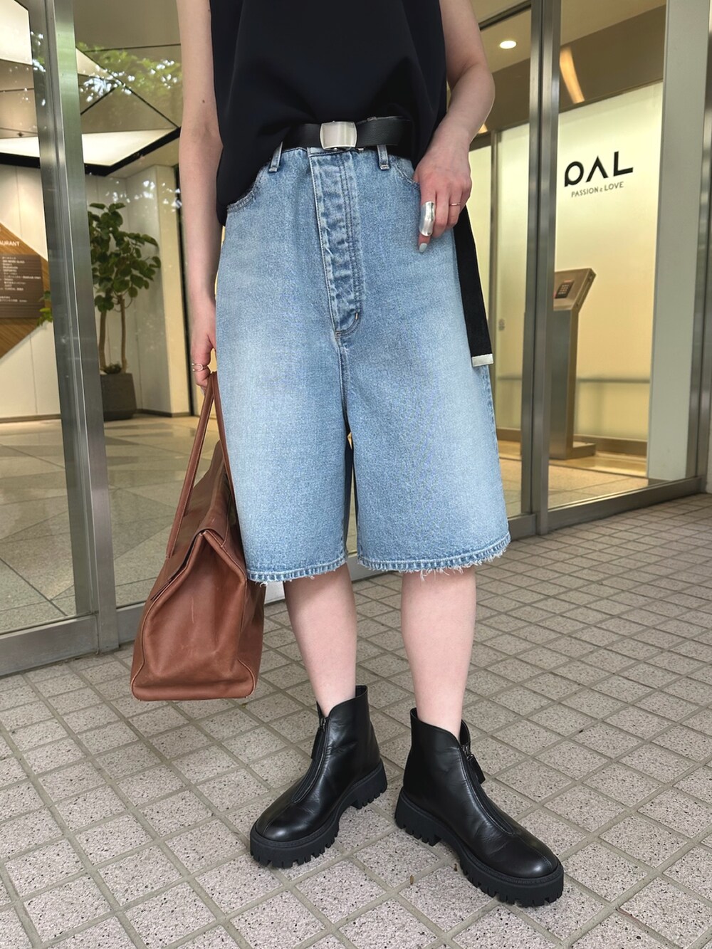 ブルー系のデニムパンツ、ブラック系のブーツ、イエロー系のボストンバッグを着用したレディースの夏コーディネートの5枚目の写真