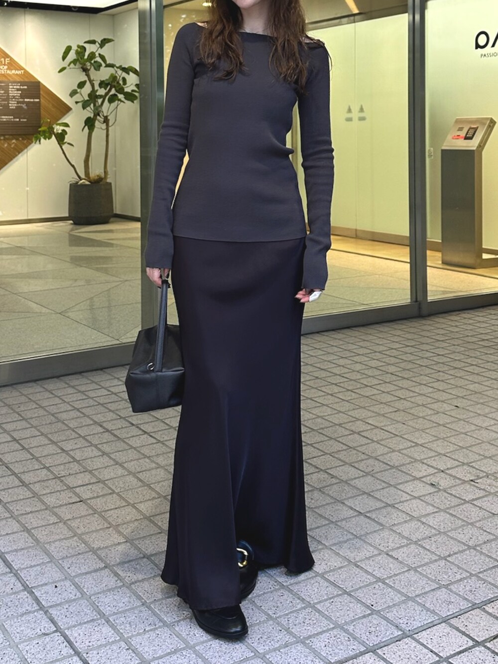 ブラック系のスカート、ブラウン系のハンドバッグ、グレー系のニット/セーターを着用したレディースの夏コーディネートの5枚目の写真