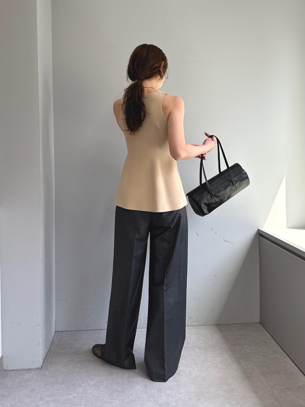 グレー系のスラックス、ホワイト系のハンドバッグ、ブラック系のパンプスを着用したレディースの春コーディネートの3枚目の写真