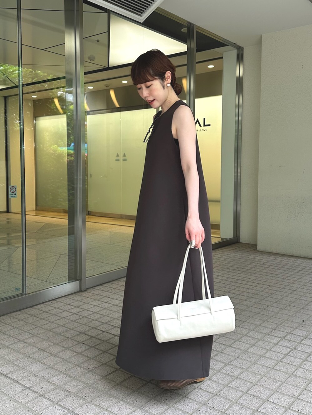 グレー系のワンピース、ホワイト系のハンドバッグ、ブラック系のパンプスを着用したレディースの夏コーディネートの4枚目の写真
