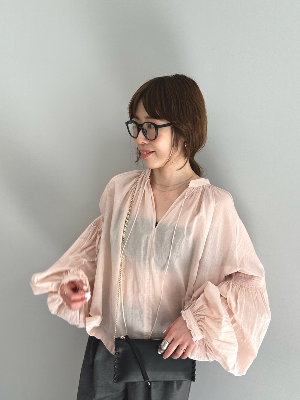 ピンク系のシャツ/ブラウス、グレー系のスラックス、ブラック系のショルダーバッグを着用したレディースの春コーディネートの6枚目の写真