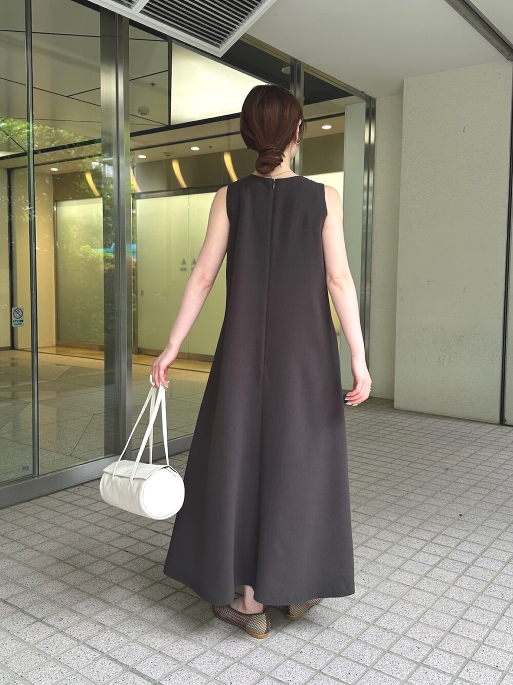 グレー系のワンピース、ホワイト系のハンドバッグ、ブラック系のパンプスを着用したレディースの夏コーディネートの3枚目の写真