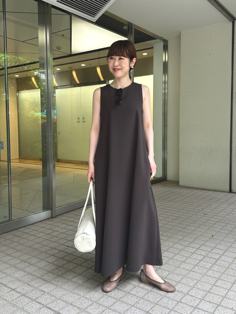 グレー系のワンピース、ホワイト系のハンドバッグ、ブラック系のパンプスを着用したレディースの夏コーディネートの2枚目の写真