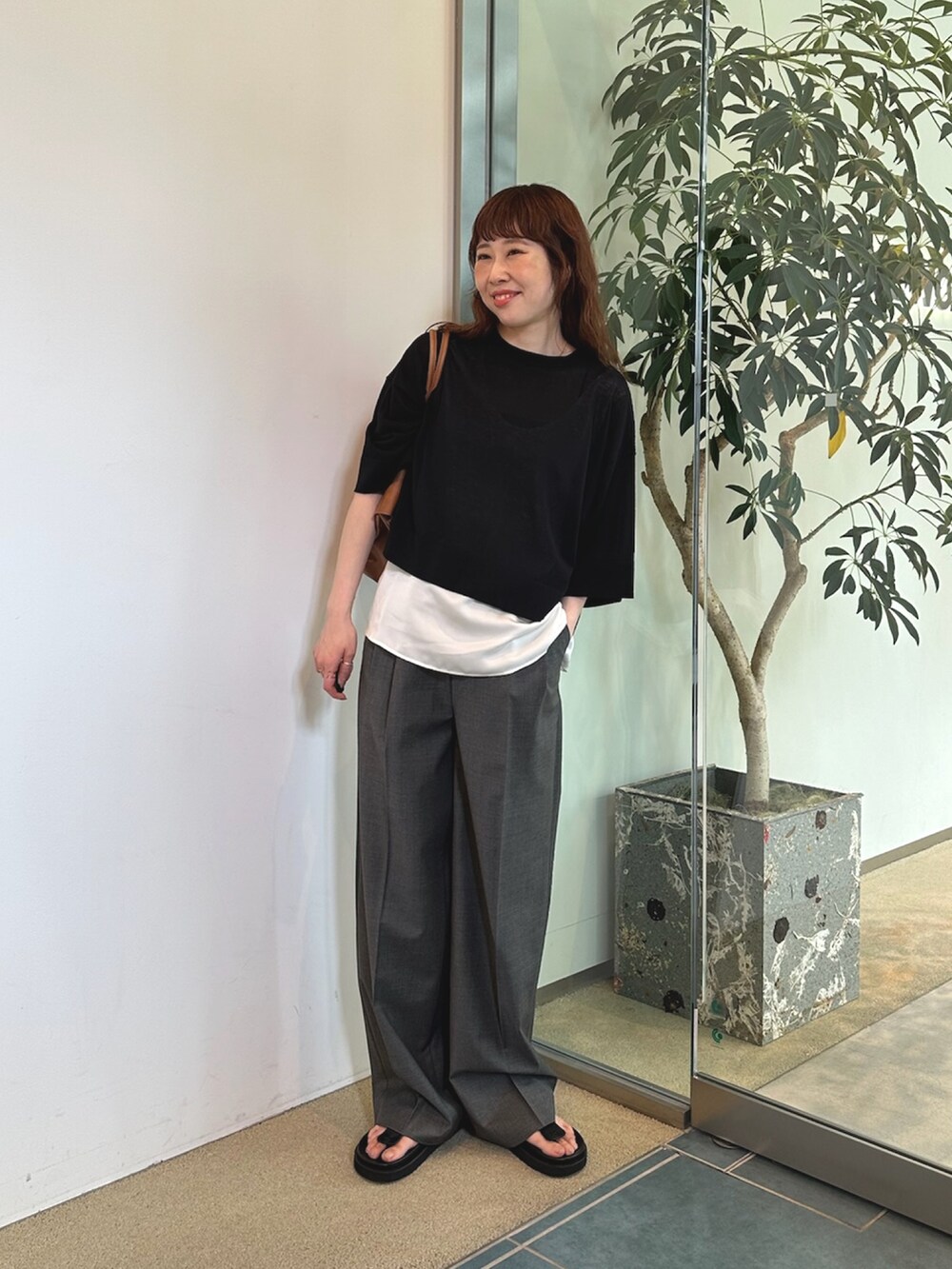 グレー系のスラックス、イエロー系のボストンバッグ、ホワイト系のシャツ/ブラウスを着用したレディースの夏コーディネートの2枚目の写真