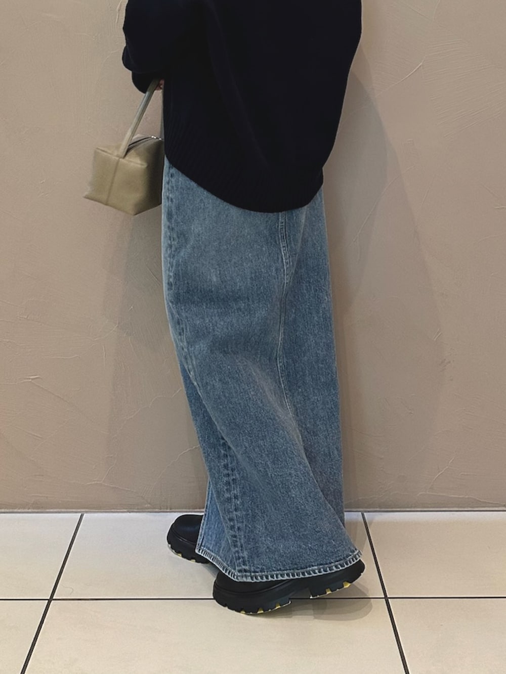 ブルー系のデニムスカート、ブラック系のブーツ、ブラウン系のハンドバッグを着用したレディースの夏コーディネートの4枚目の写真