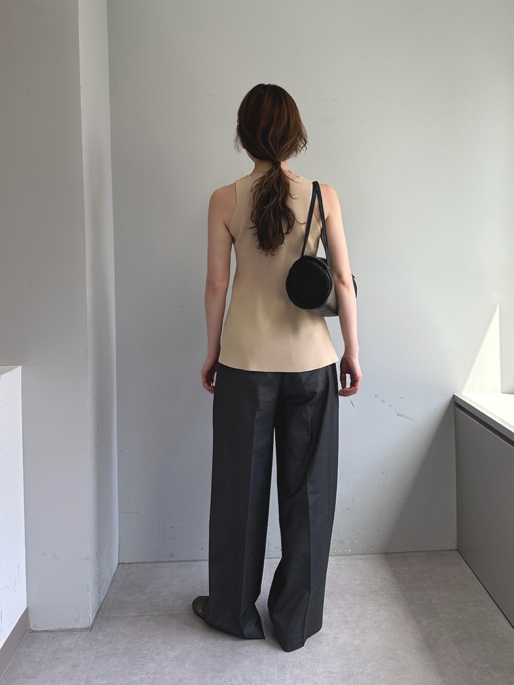 グレー系のスラックス、ホワイト系のハンドバッグ、ブラック系のパンプスを着用したレディースの春コーディネートの4枚目の写真