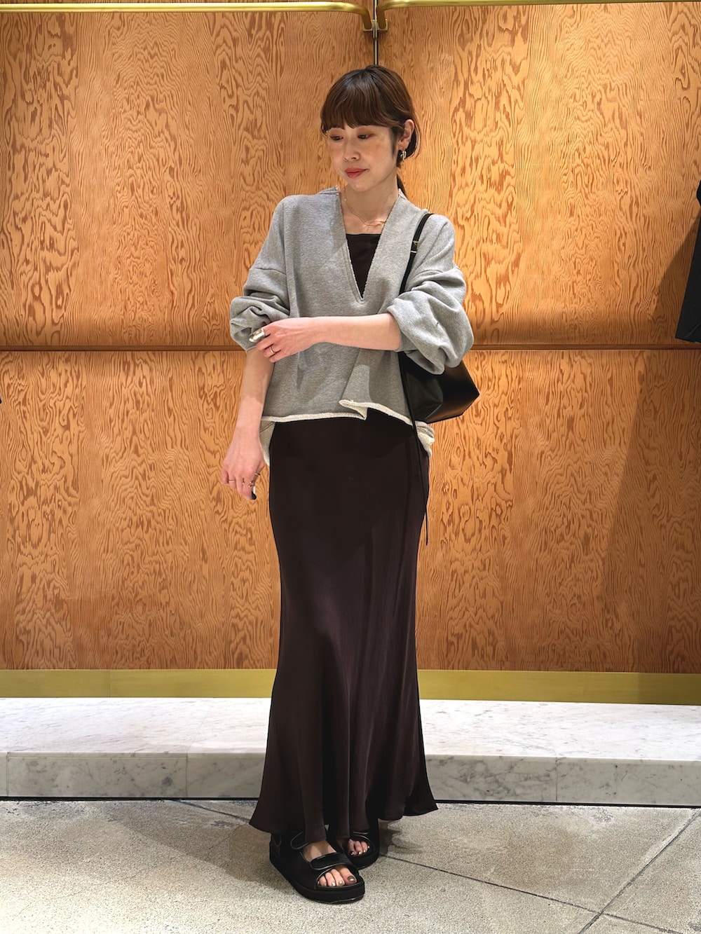 ホワイト系のスウェット、ブラック系のサンダル、ブラウン系のショルダーバッグを着用したレディースの春コーディネートの4枚目の写真