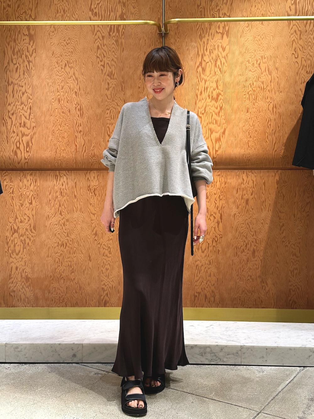 ホワイト系のスウェット、ブラック系のサンダル、ブラウン系のショルダーバッグを着用したレディースの春コーディネートの5枚目の写真