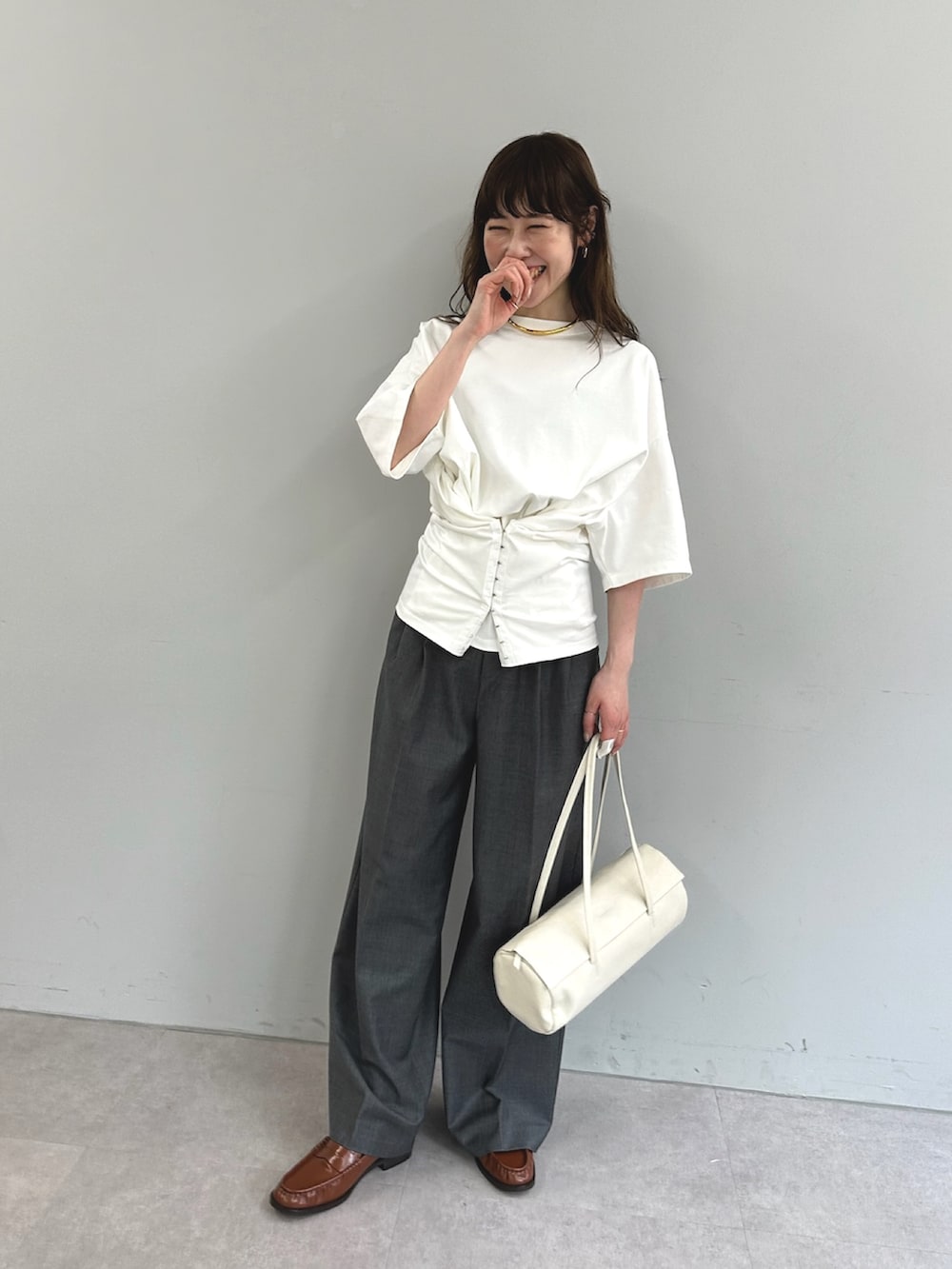 ホワイト系のTシャツ/カットソー、ホワイト系のハンドバッグ、グレー系のスラックスを着用したレディースの春コーディネートの5枚目の写真