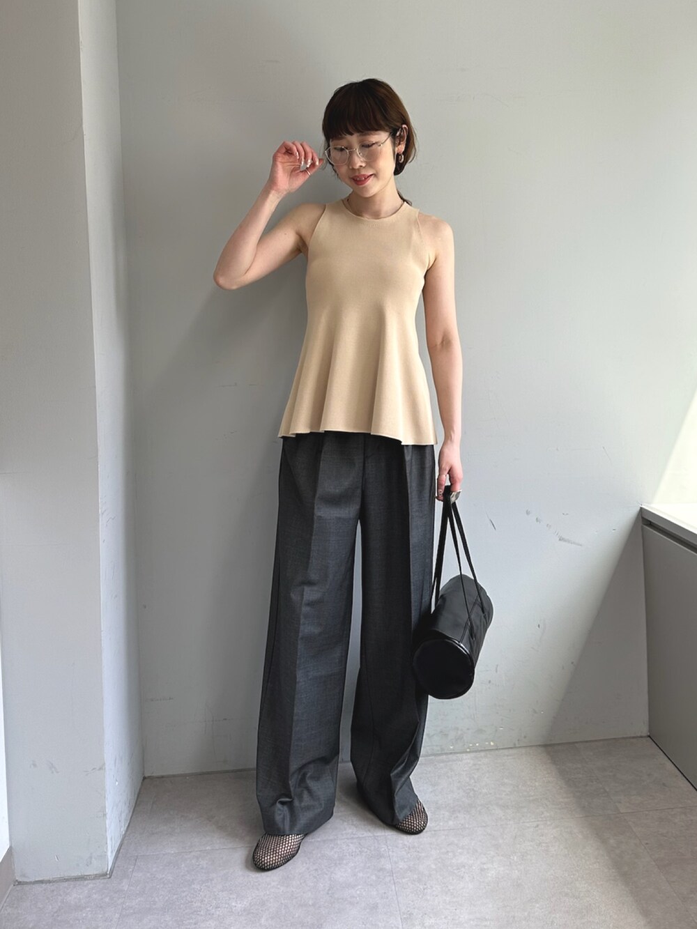 グレー系のスラックス、ホワイト系のハンドバッグ、ブラック系のパンプスを着用したレディースの春コーディネートの2枚目の写真