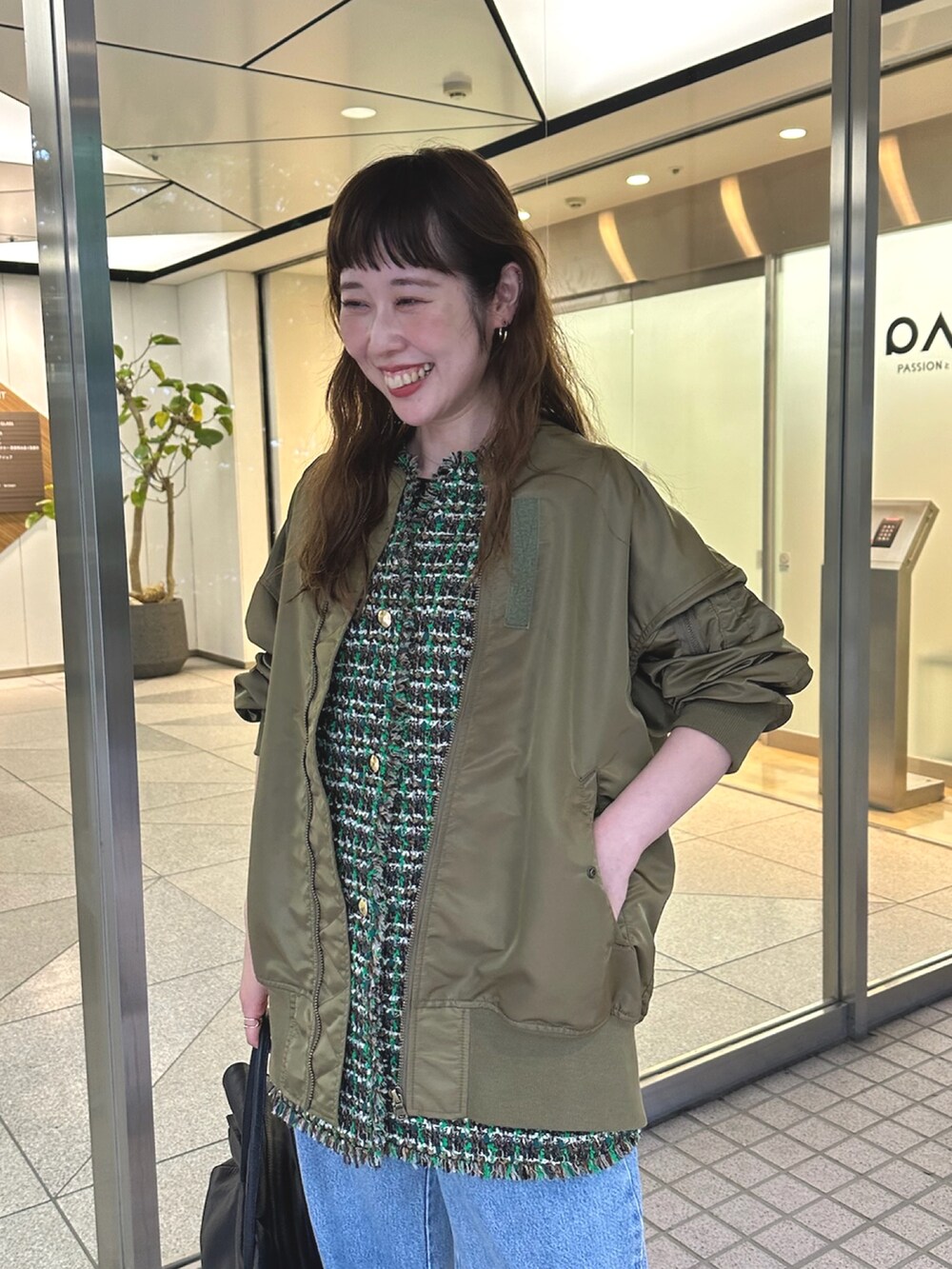 グリーン系のMA-1、ブルー系のデニムパンツ、ブラック系のボストンバッグを着用したレディースの夏コーディネートの5枚目の写真