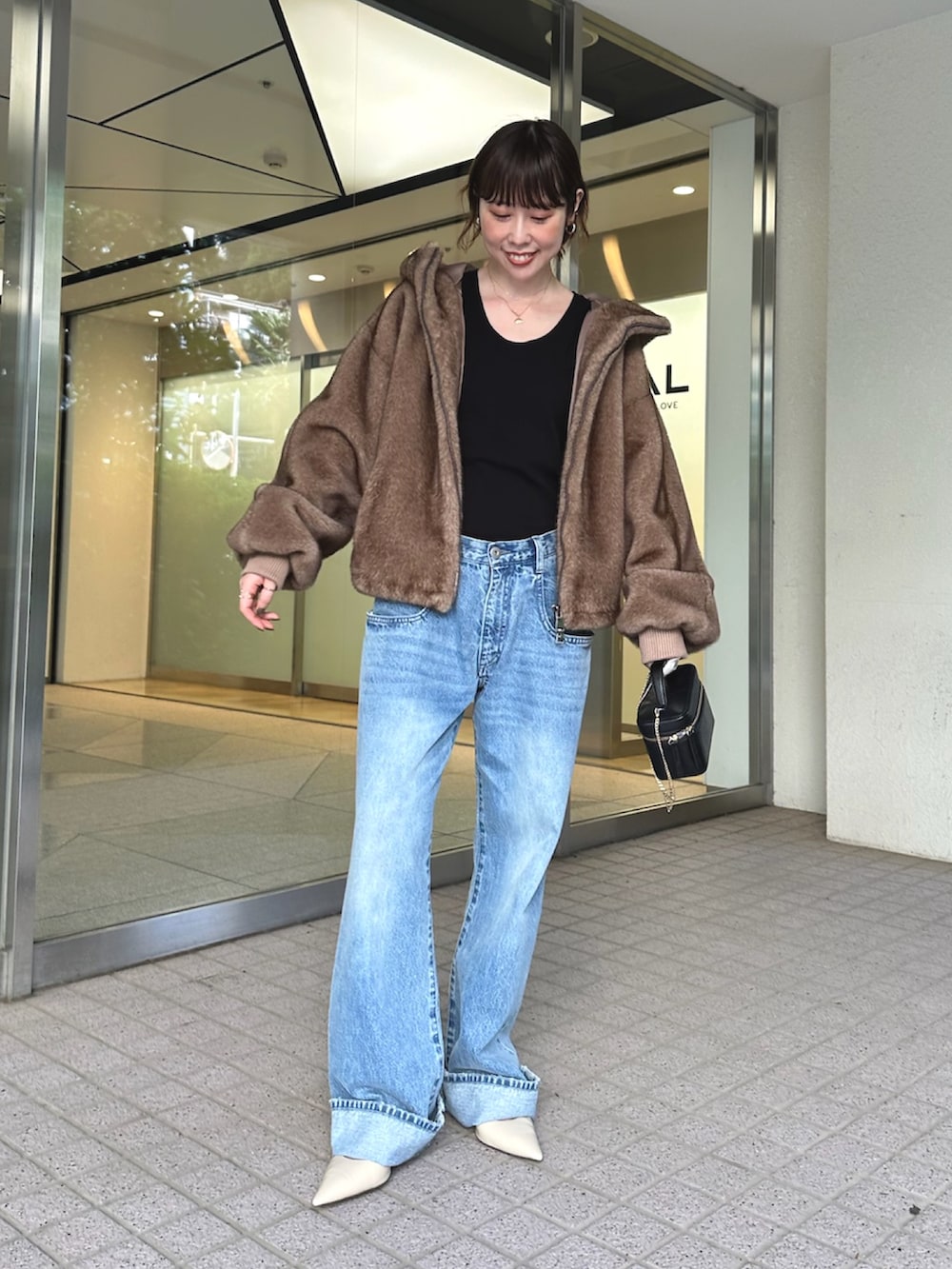 ブルー系のデニムパンツ、ブラック系のショルダーバッグ、ベージュ系のパンプスを着用したレディースの夏コーディネートの2枚目の写真