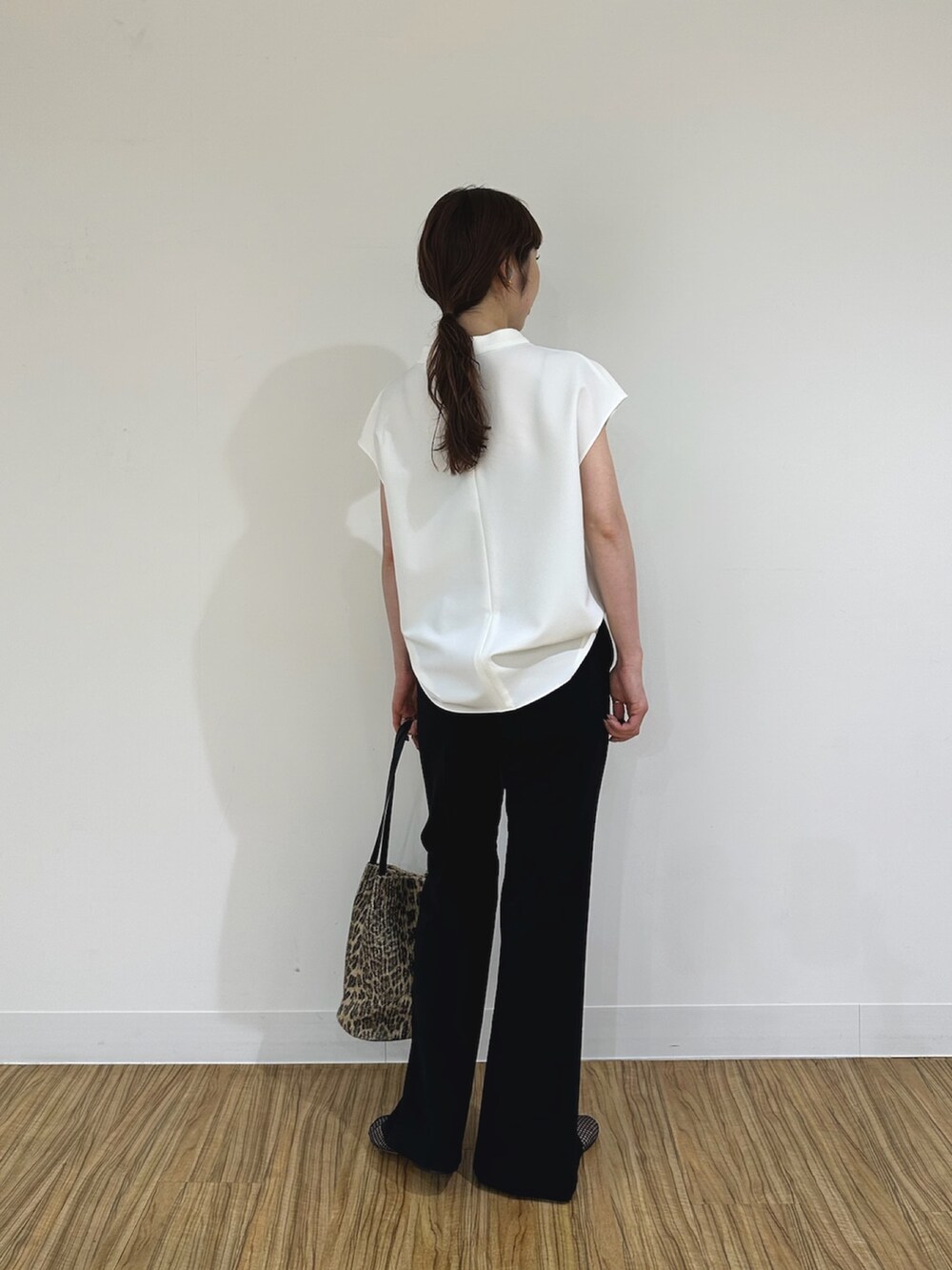 ブラック系のスラックス、ブラック系のパンプス、ホワイト系のシャツ/ブラウスを着用したレディースの夏コーディネートの2枚目の写真