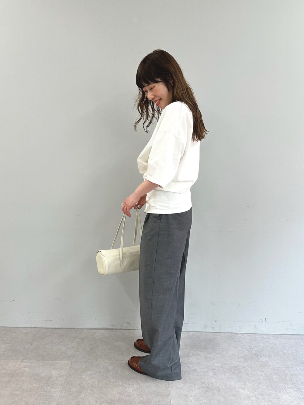 ホワイト系のTシャツ/カットソー、ホワイト系のハンドバッグ、グレー系のスラックスを着用したレディースの春コーディネートの4枚目の写真