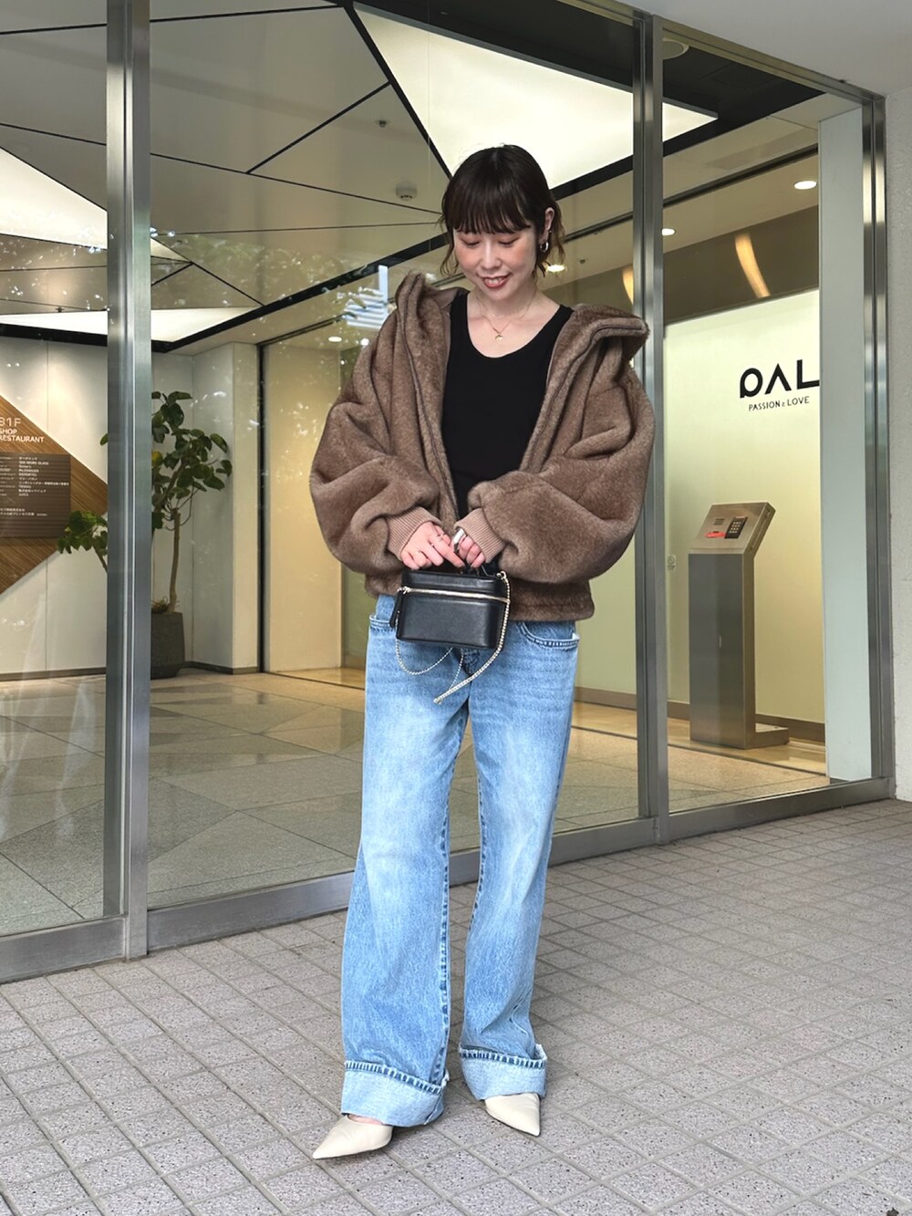 ブルー系のデニムパンツ、ブラック系のショルダーバッグ、ベージュ系のパンプスを着用したレディースの夏コーディネートの3枚目の写真