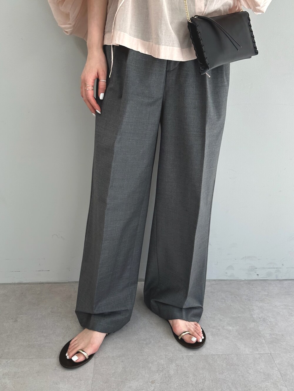 ピンク系のシャツ/ブラウス、グレー系のスラックス、ブラック系のショルダーバッグを着用したレディースの春コーディネートの7枚目の写真