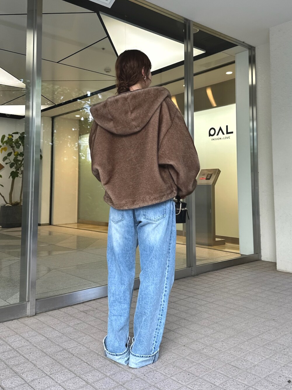 ブルー系のデニムパンツ、ブラック系のショルダーバッグ、ベージュ系のパンプスを着用したレディースの夏コーディネートの4枚目の写真