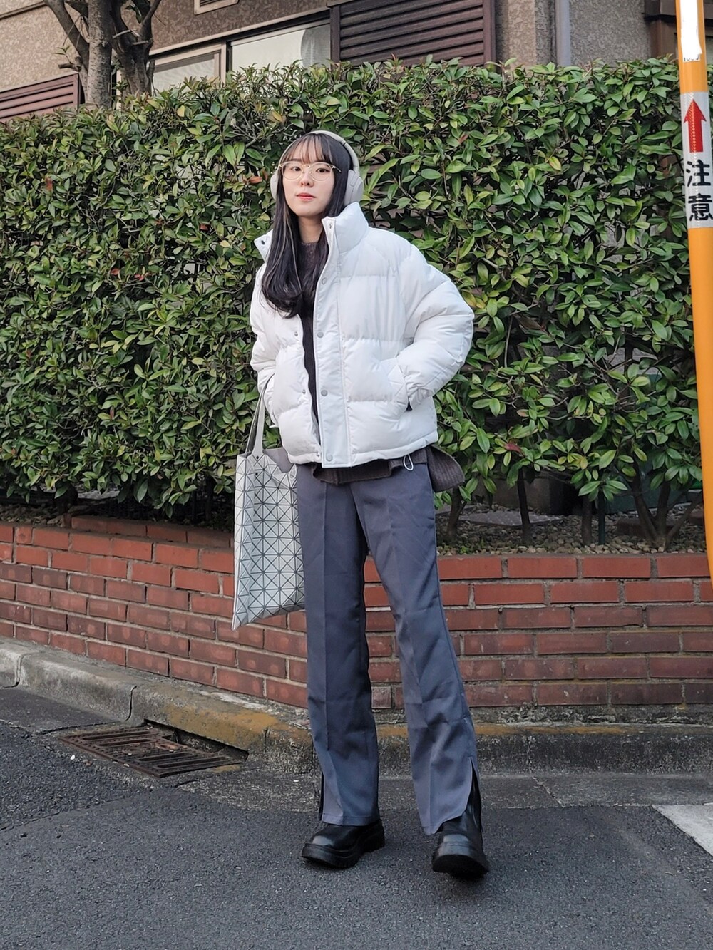 ホワイト系のダウンジャケット/コート、グレー系のニット/セーター、グレー系のスラックスを着用したレディースの冬コーディネートの4枚目の写真