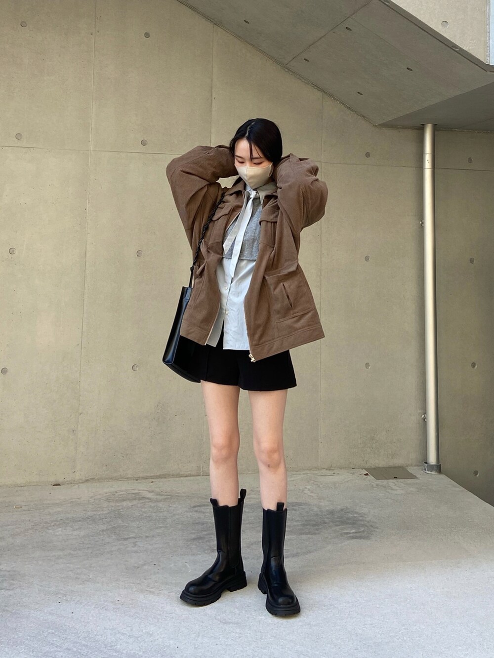 ブラウン系のブルゾン、ブルー系のシャツ/ブラウス、グレー系のニット/セーターを着用したレディースの秋コーディネートの2枚目の写真