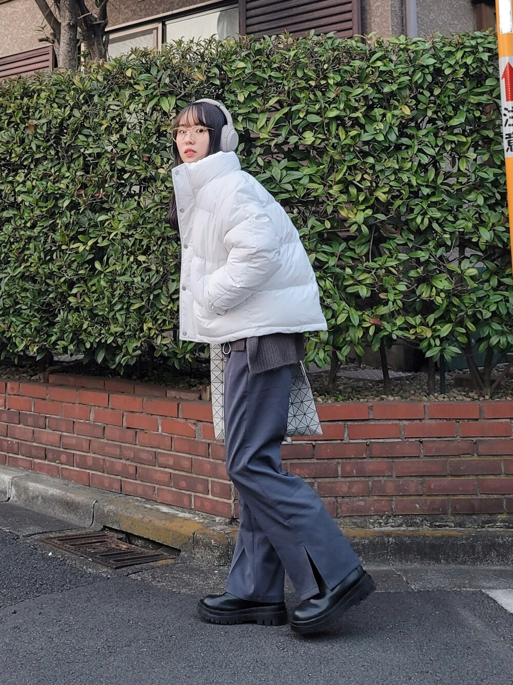 ホワイト系のダウンジャケット/コート、グレー系のニット/セーター、グレー系のスラックスを着用したレディースの冬コーディネートの2枚目の写真