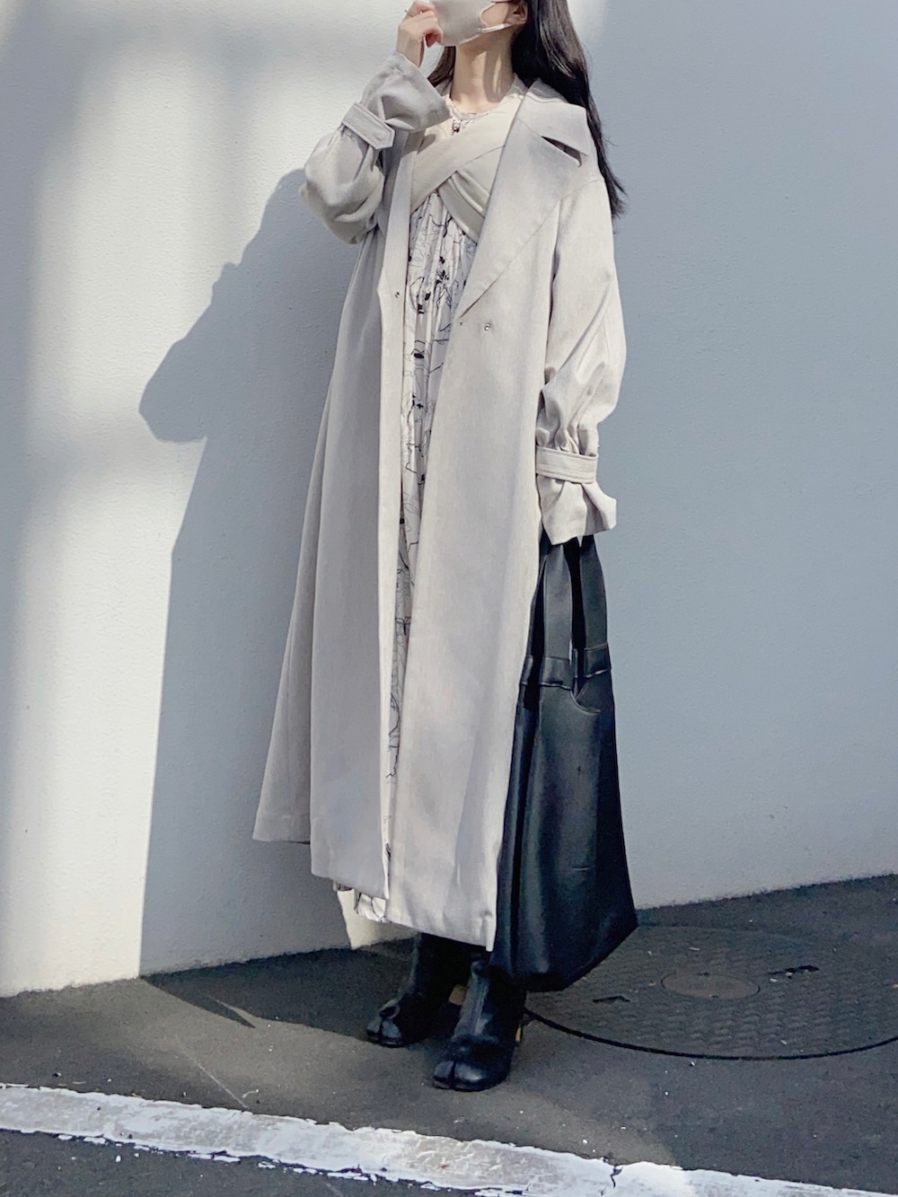 ベージュ系のワンピース、ホワイト系のトレンチコート、ベージュ系のベストを着用したレディースの春コーディネートの2枚目の写真