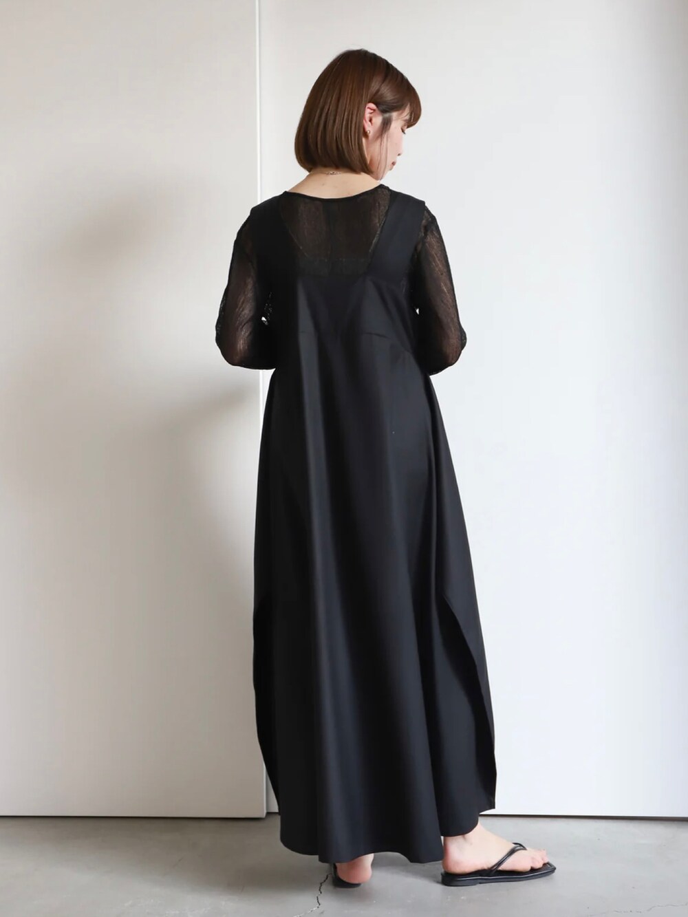 ブラック系のニット/セーター、ブラック系のジャンパースカートを着用したレディースの春コーディネートの2枚目の写真