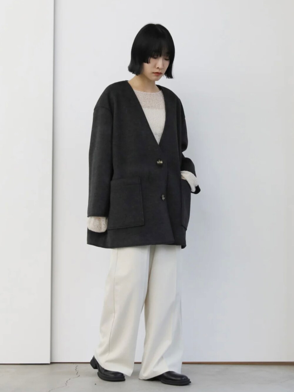 ブラック系のノーカラーコート、ホワイト系のニット/セーター、ホワイト系のスラックスを着用したレディースの秋コーディネートの5枚目の写真