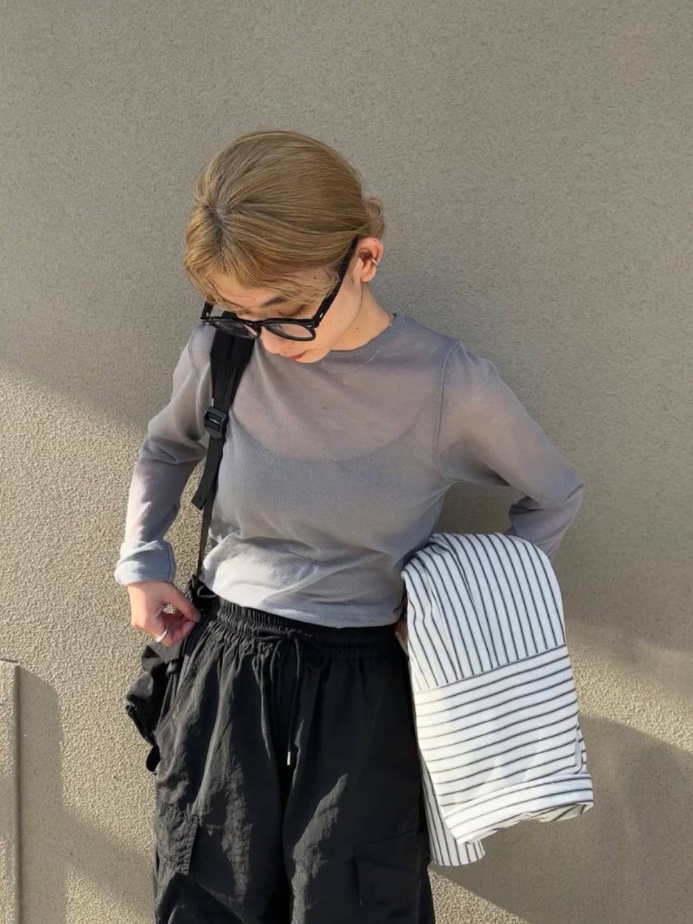 グレー系のニット/セーター、ホワイト系のシャツ/ブラウス、ブラック系のカーゴパンツを着用したレディースの春コーディネートの3枚目の写真