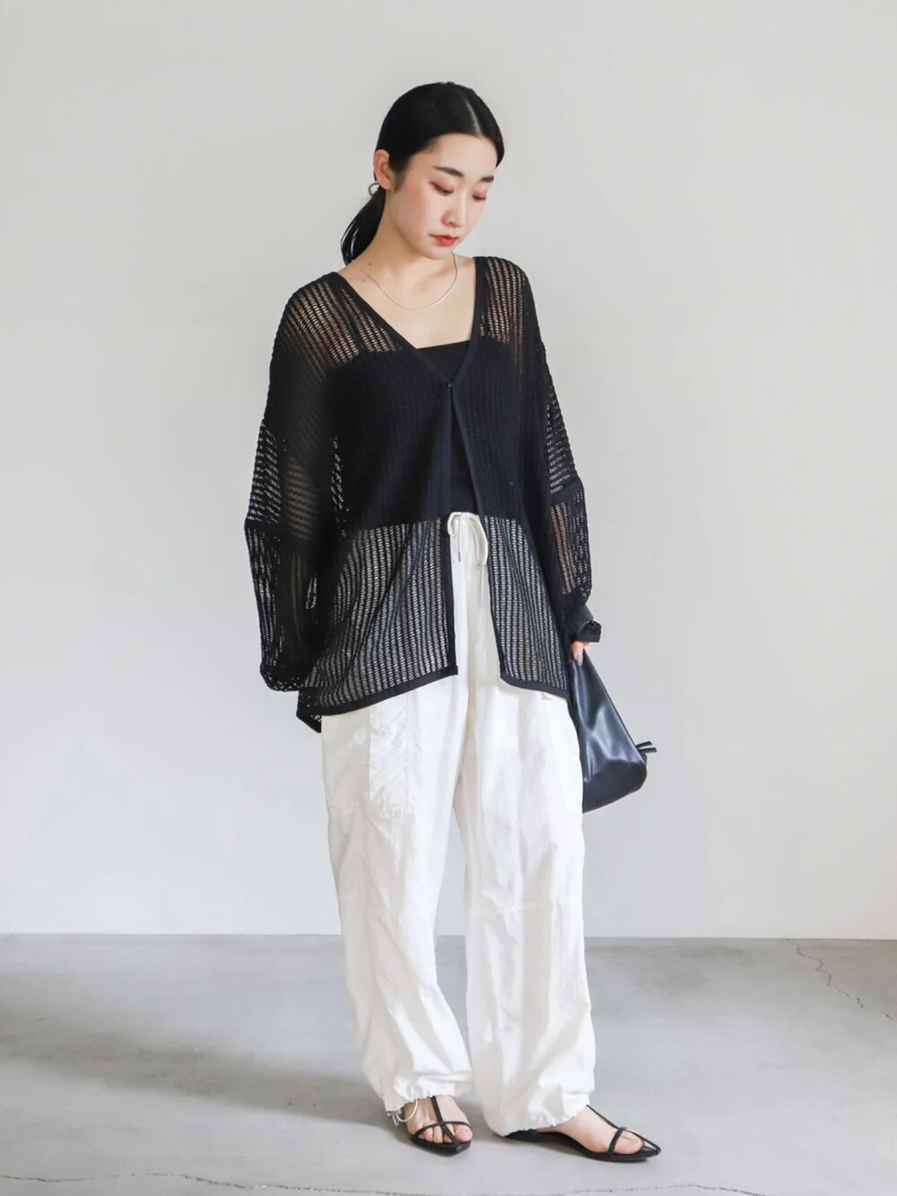 ブラック系のカーディガン/ボレロ、ブラック系のキャミソール、ホワイト系のカーゴパンツを着用したレディースの春コーディネートの2枚目の写真