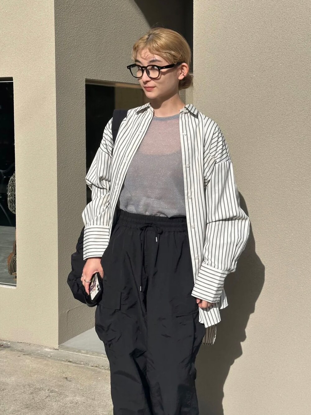 グレー系のニット/セーター、ホワイト系のシャツ/ブラウス、ブラック系のカーゴパンツを着用したレディースの春コーディネートの5枚目の写真