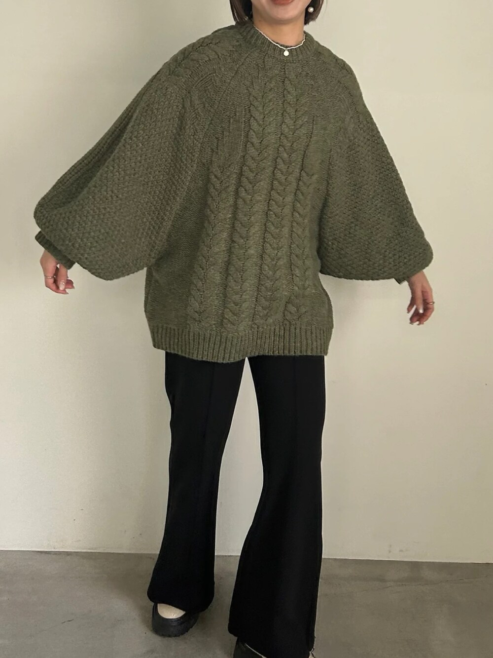 グリーン系のニット/セーター、ブラック系のその他パンツを着用したレディースの冬コーディネートの5枚目の写真