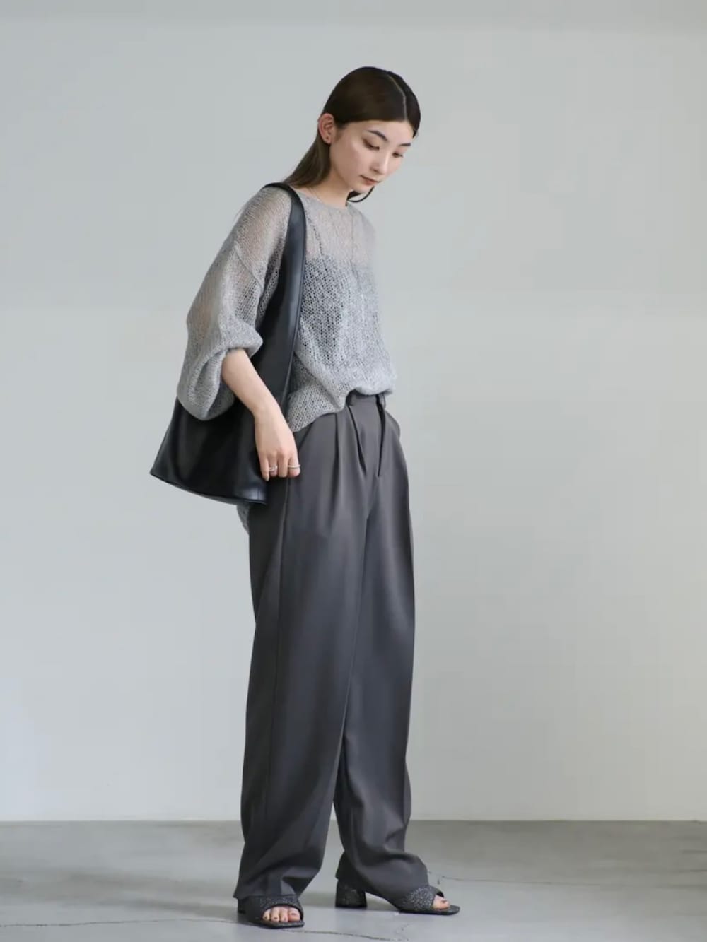 グレー系のニット/セーター、グレー系のスラックス、ブラック系のサンダルを着用したレディースの夏コーディネートの5枚目の写真