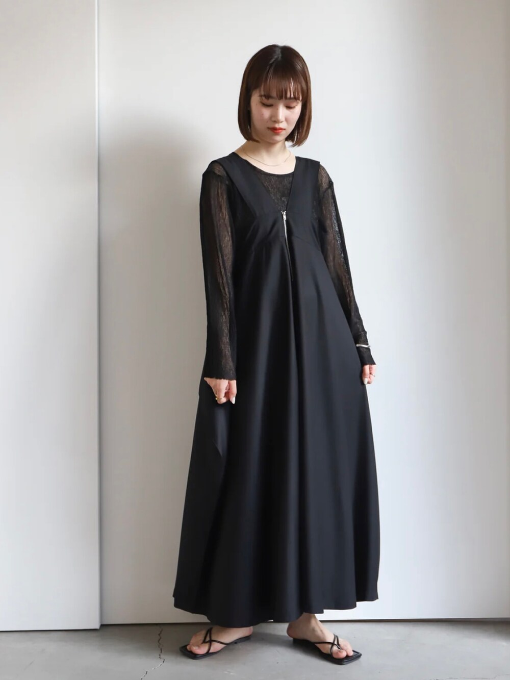 ブラック系のニット/セーター、ブラック系のジャンパースカートを着用したレディースの春コーディネートの4枚目の写真