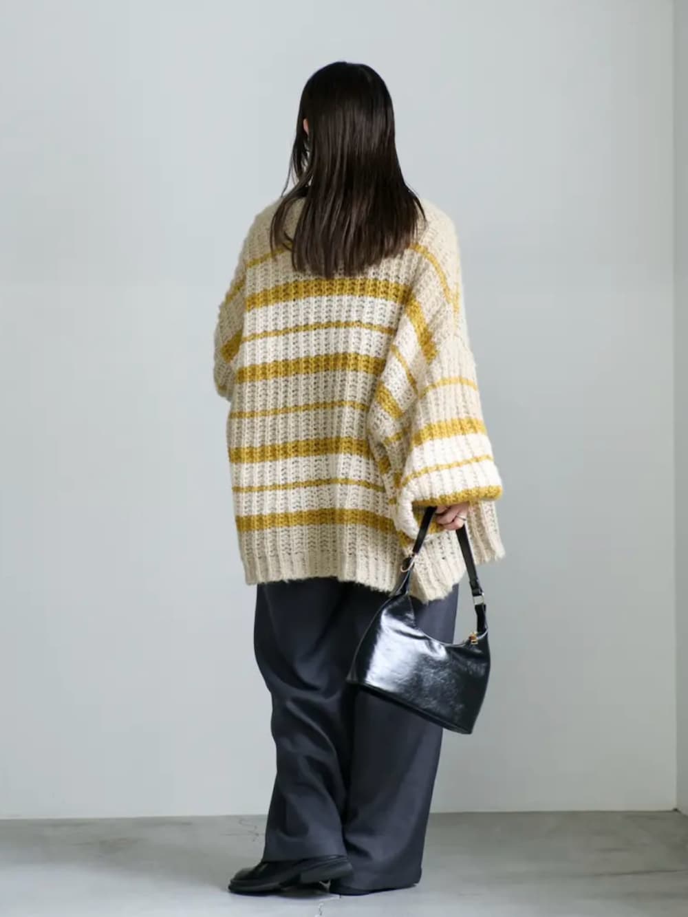 イエロー系のカーディガン/ボレロ、ホワイト系のニット/セーター、ブラック系のハンドバッグを着用したレディースの秋コーディネートの3枚目の写真