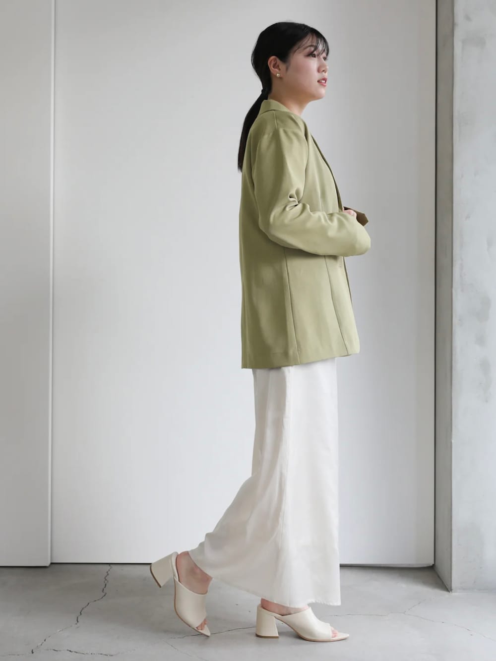 グリーン系のテーラードジャケット、ホワイト系のスカート、グリーン系のTシャツ/カットソーを着用したレディースの冬コーディネートの5枚目の写真