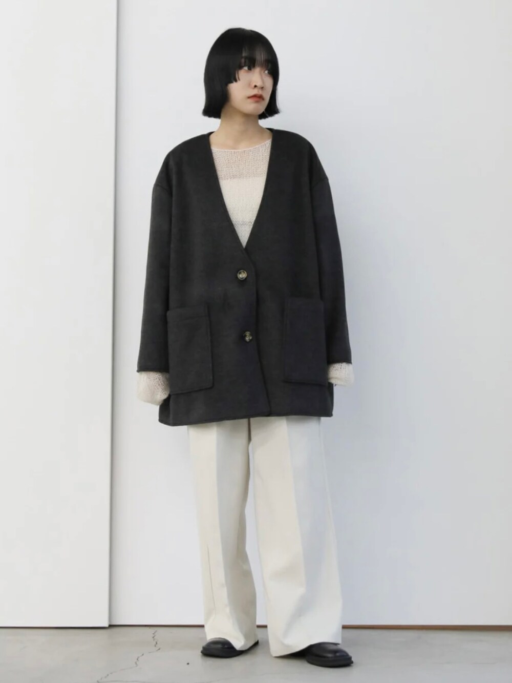 ブラック系のノーカラーコート、ホワイト系のニット/セーター、ホワイト系のスラックスを着用したレディースの秋コーディネートの4枚目の写真