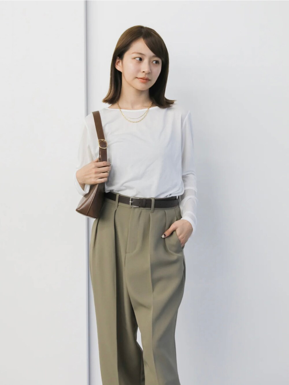 ホワイト系のTシャツ/カットソー、ベージュ系のスラックス、ブラウン系のハンドバッグを着用したレディースの冬コーディネートの3枚目の写真