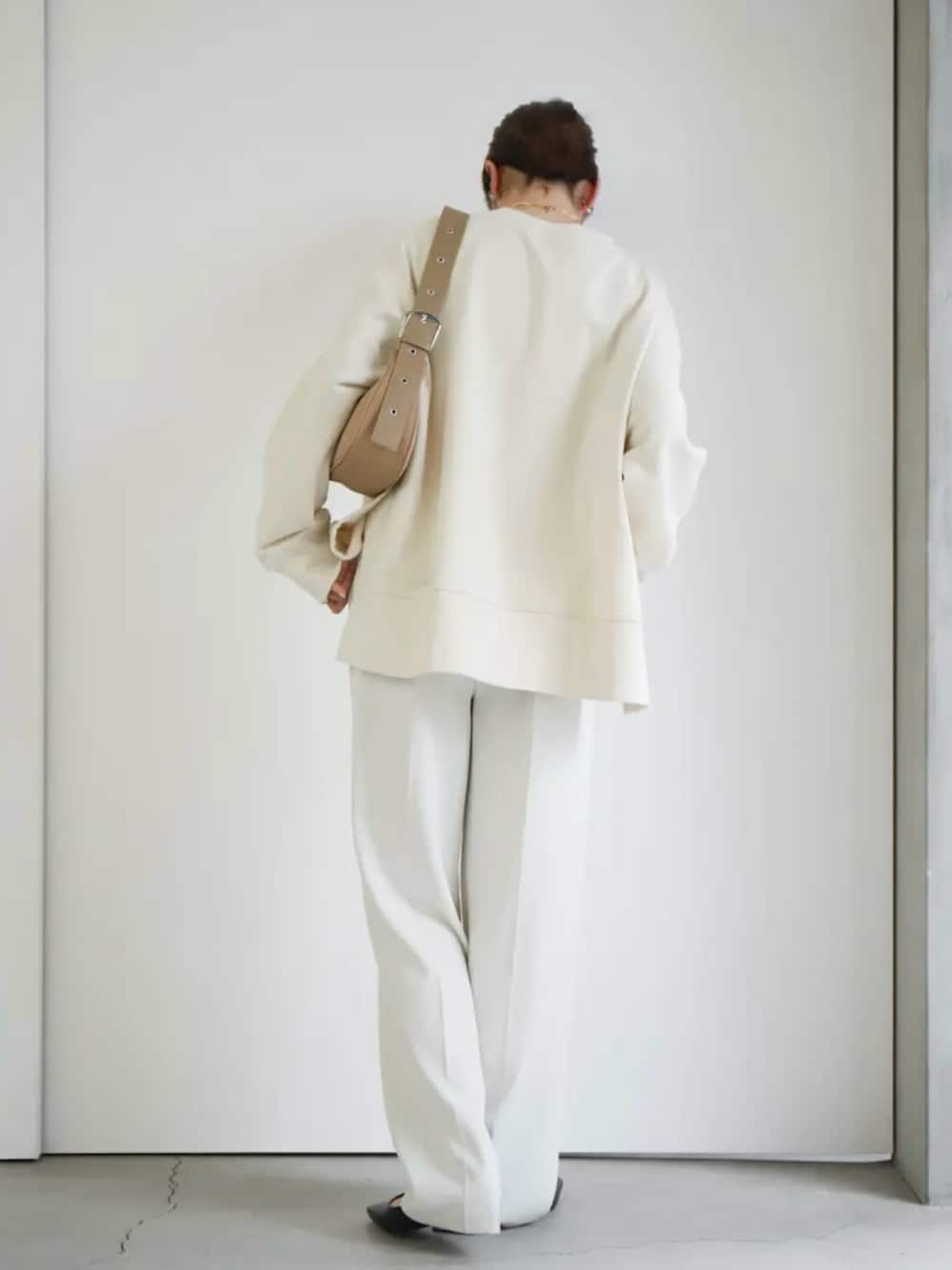 ホワイト系のスウェット、ホワイト系のスラックス、ベージュ系のショルダーバッグを着用したレディースの冬コーディネートの4枚目の写真
