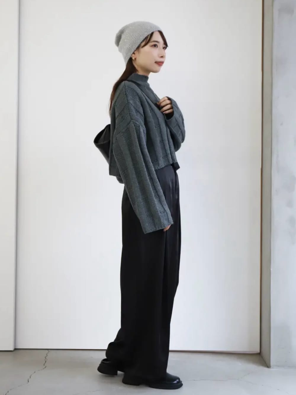 ブラック系のスラックス、ブラック系のショルダーバッグ、グレー系のニット/セーターを着用したレディースの冬コーディネートの3枚目の写真